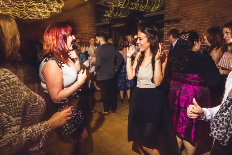 Guests dancing and singing together in the crowded barn