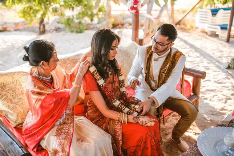 Relatives tying the bride and groom's garlands during the ceremony on the red daybed