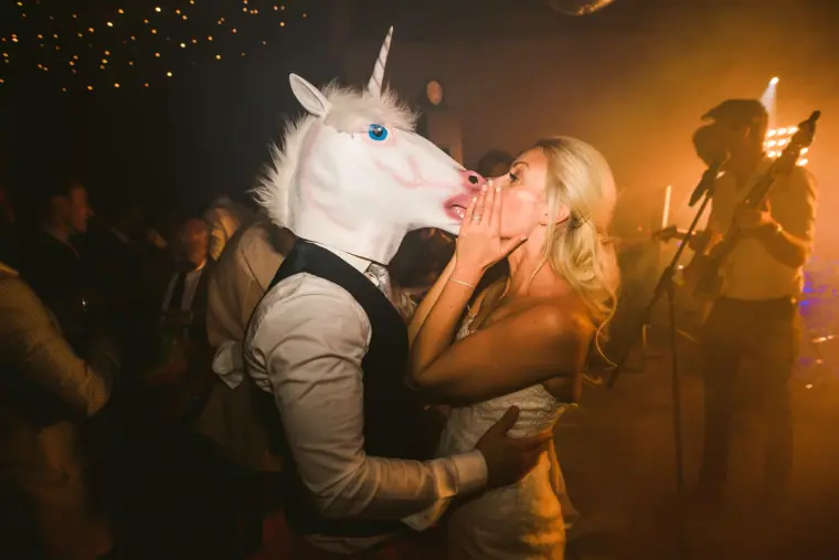 Guest in a unicorn mask kissing a laughing woman on the dance floor, Chateau Rigaud