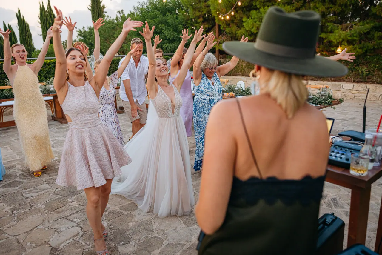 Bride and friends dancing with arms raised as a singer in a hat performs