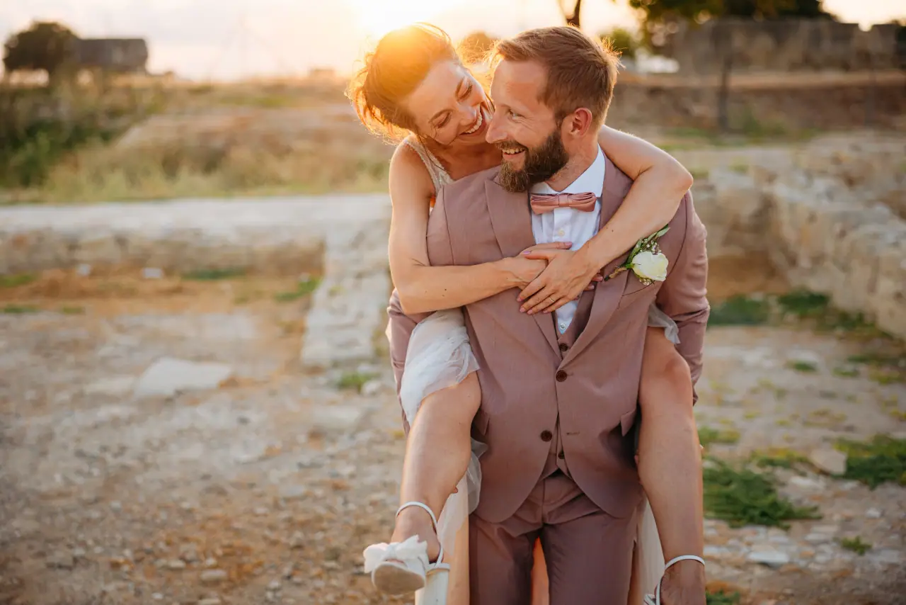 Vanja riding piggyback on Simon in his pink suit, both laughing in the evening sun