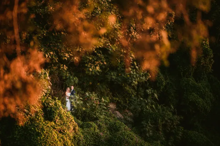 Small figure of a bride amid dense greenery and autumn-coloured foliage