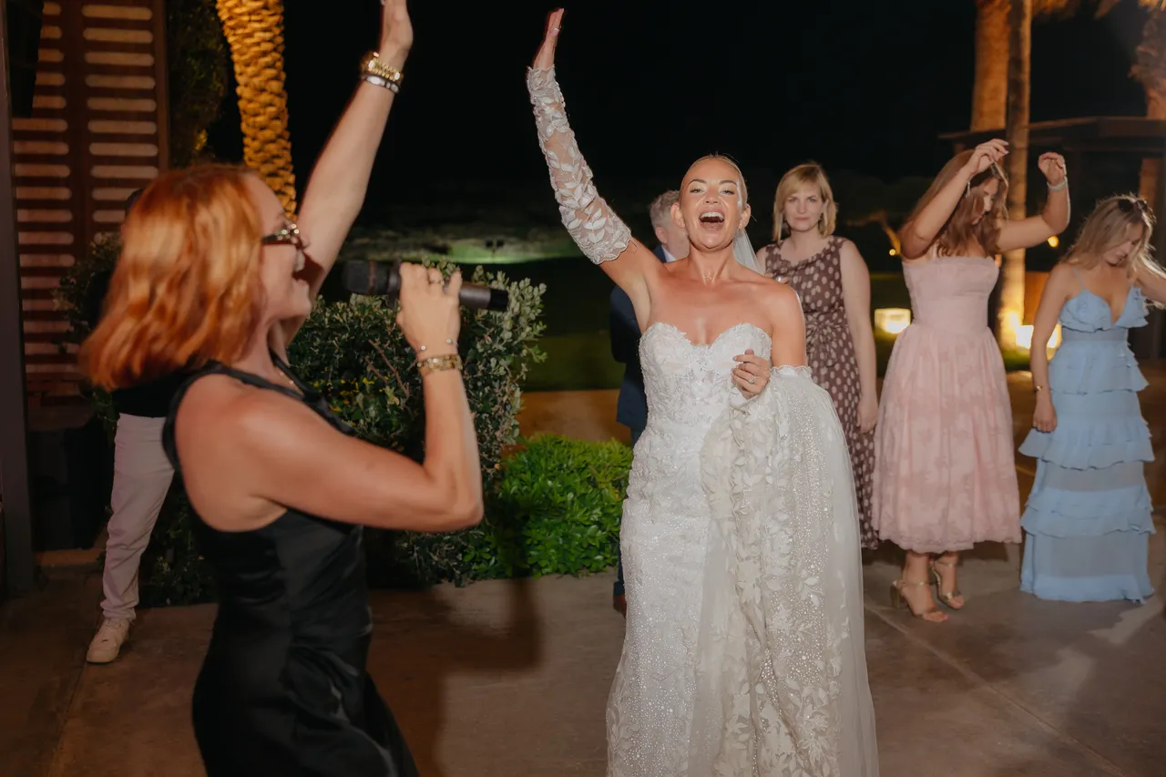 Bride singing along with arms raised beside the singer
