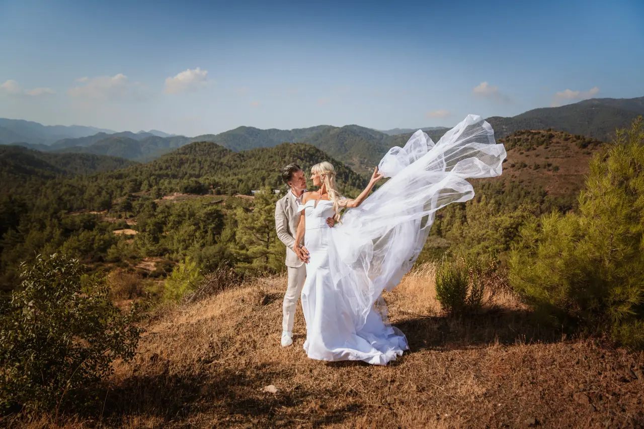 Bride's dress caught by the wind on a hillside overlooking the Troodos Mountains