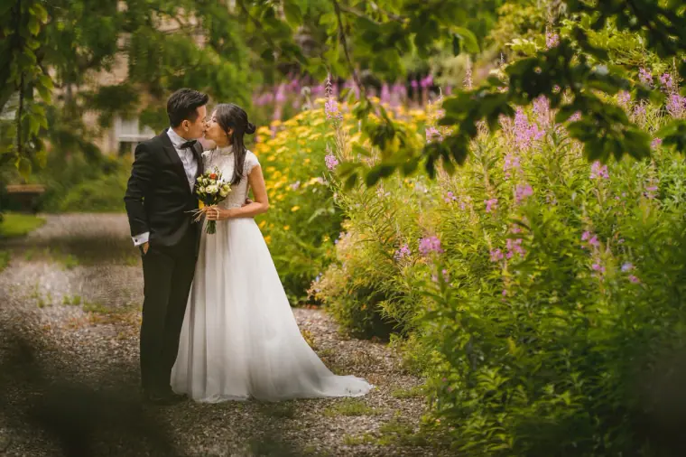 Couple kissing on a garden path among pink wildflowers in Scotland