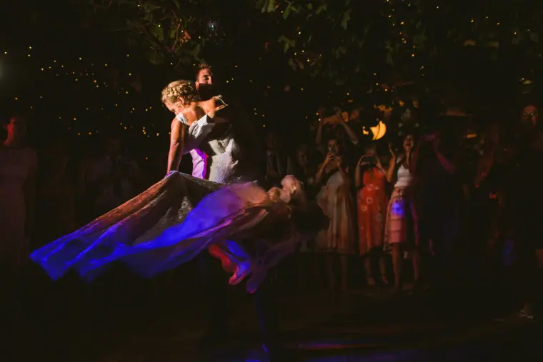 Groom dipping his bride on the dance floor in purple light at night, Pissouri