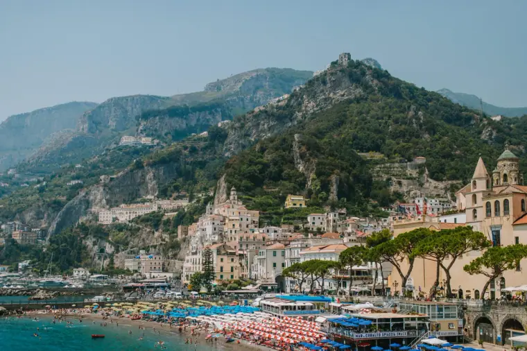 Colourful town and beach nestled below steep green mountains on the Amalfi Coast