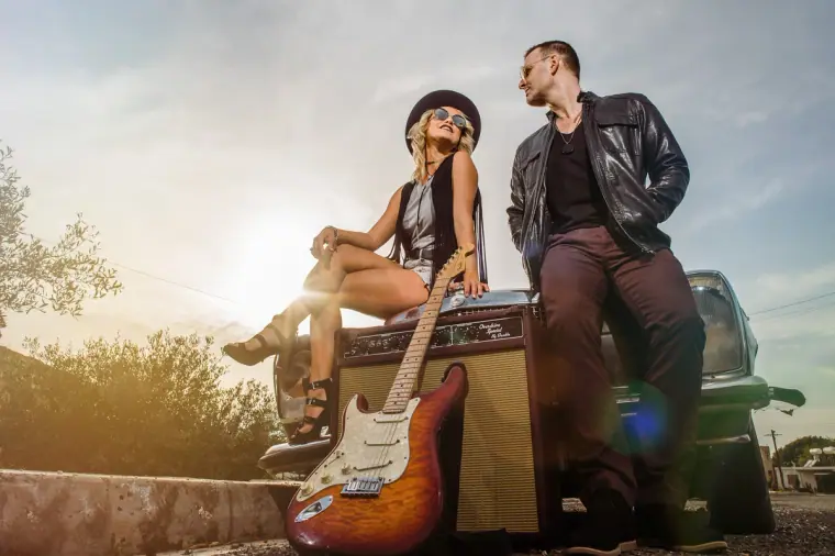 Davey and Aimie with an electric guitar and amp beside a car at sunset, Paphos