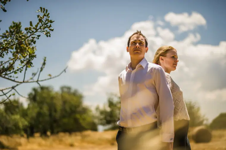 Eloping couple standing in a sunlit meadow under a blue sky, Anassa, Cyprus