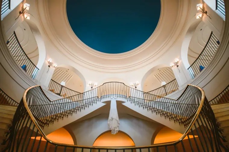 Looking up at a sweeping double staircase beneath a domed skylight, Anassa