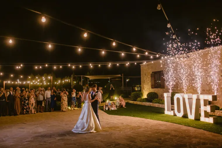First dance under festoon lights beside giant LOVE letters and cold sparklers