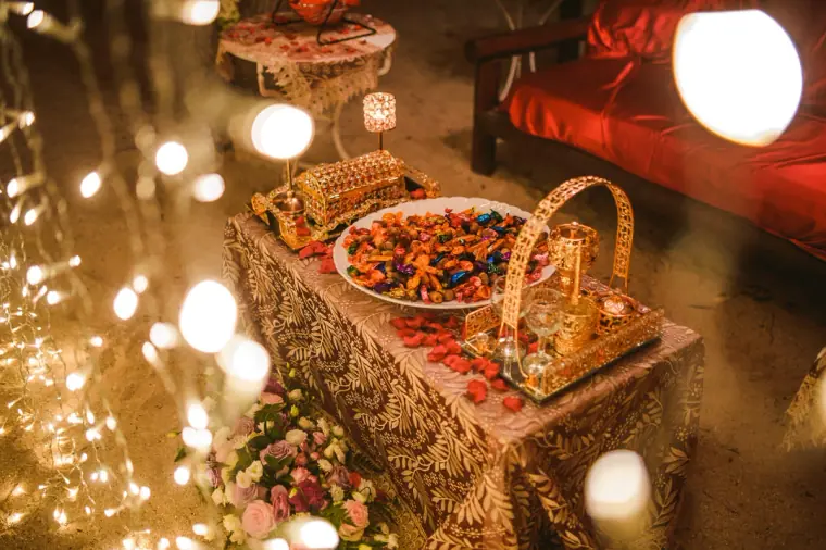 Platter of sweets and a gold basket on a table surrounded by twinkling lights
