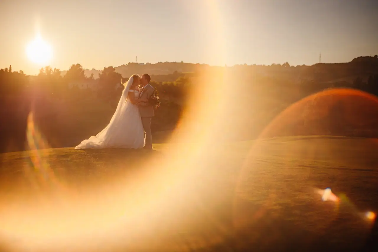 Jade and Stuart embracing at sunset with golden lens flare at Minthis