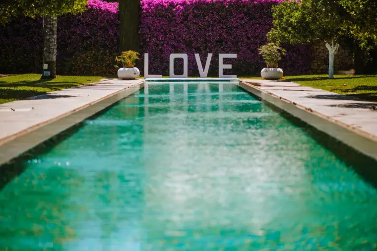 Long turquoise pool leading to LOVE letters against a pink bougainvillea wall, Ibiza