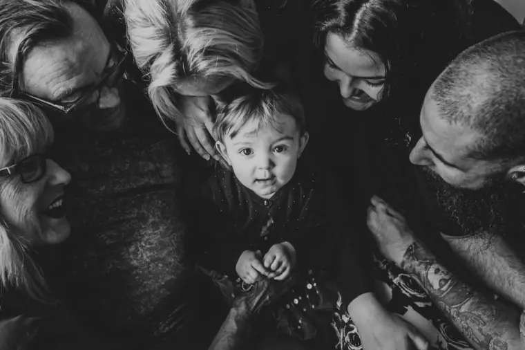 Black-and-white photo of a family huddled around a toddler looking up at the camera, Paphos