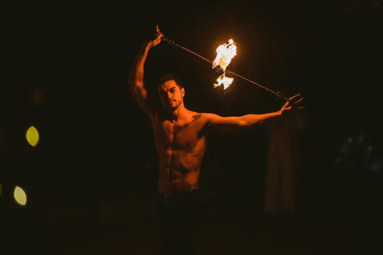 Fire dancer swinging a flaming rope above his head at night