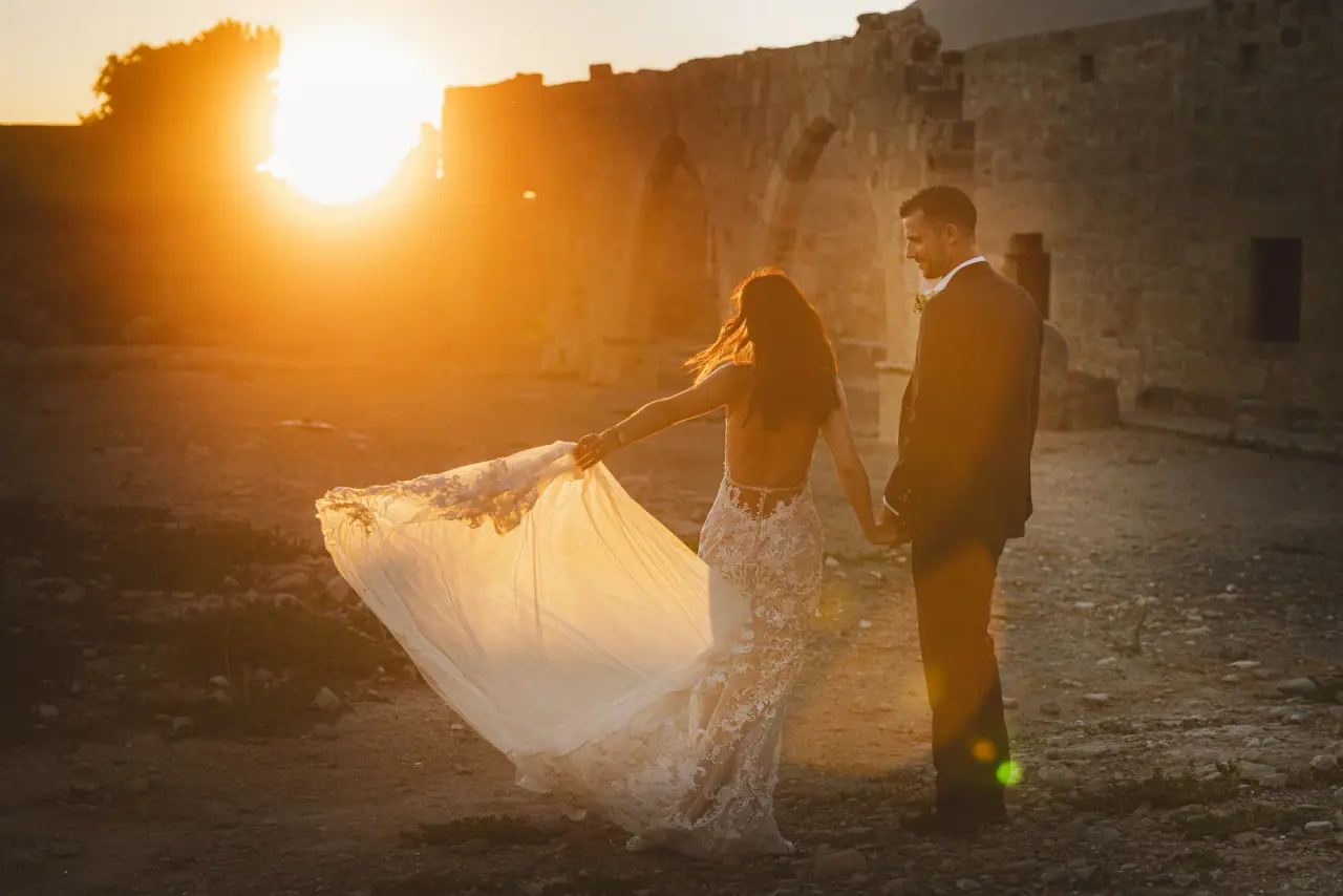 Kayleigh swishing her dress beside Ryan in sunlit stone ruins at Liopetro