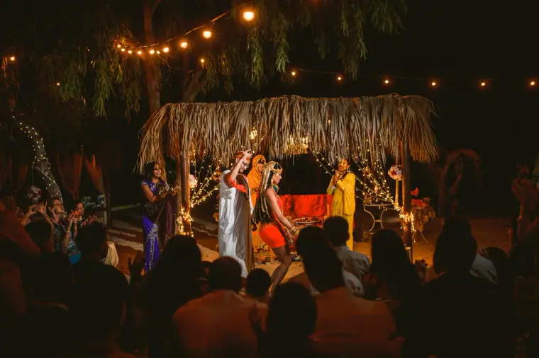 Bride dancing under the canopy as guests look on beneath festoon lights, Thalassines Beach Villas