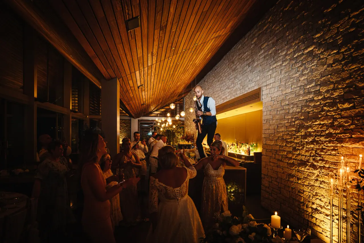 Guests mingling in a warmly lit, wood-ceilinged reception room at Minthis