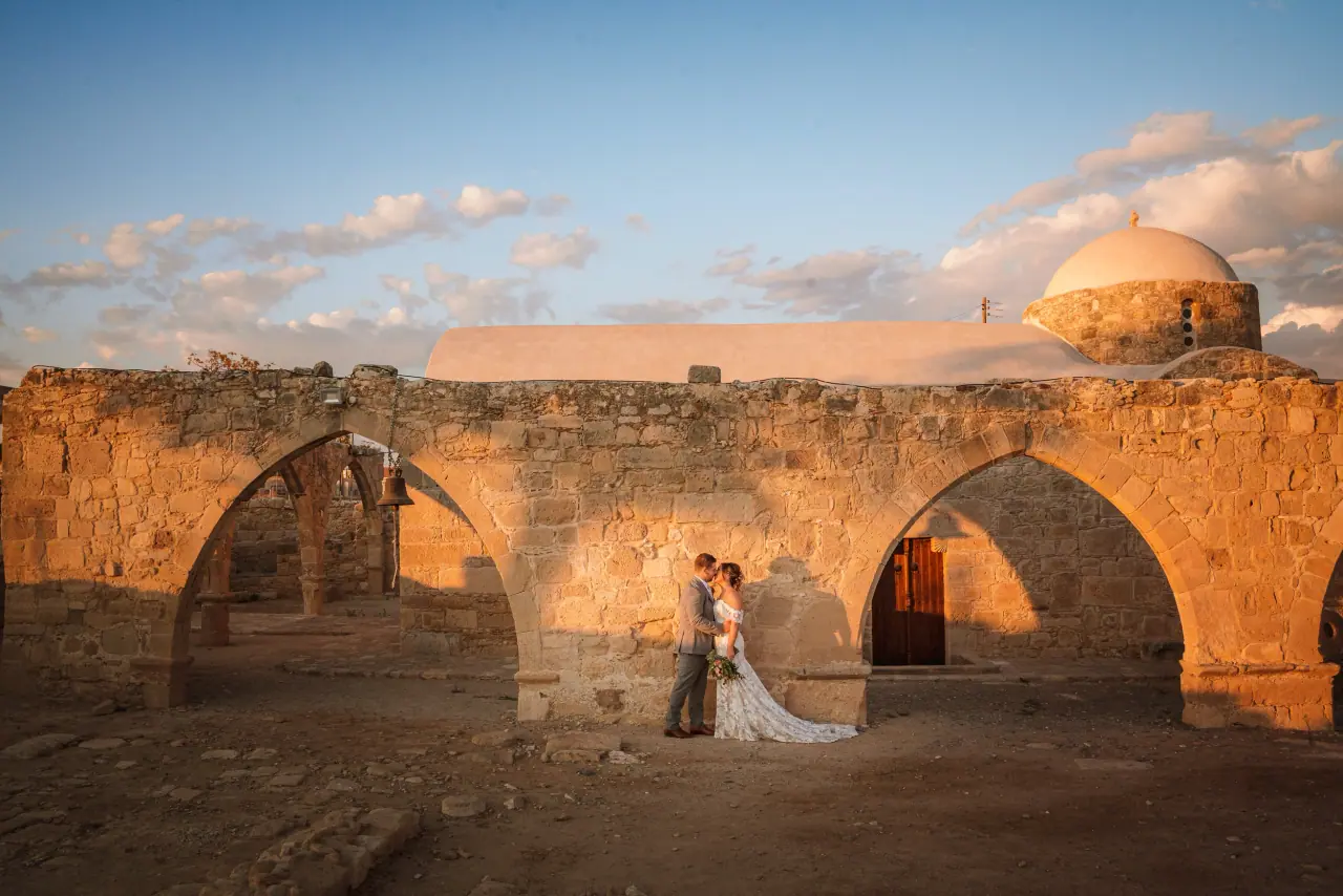 Rachel and James among stone arches with a domed church behind, Liopetro, Kouklia