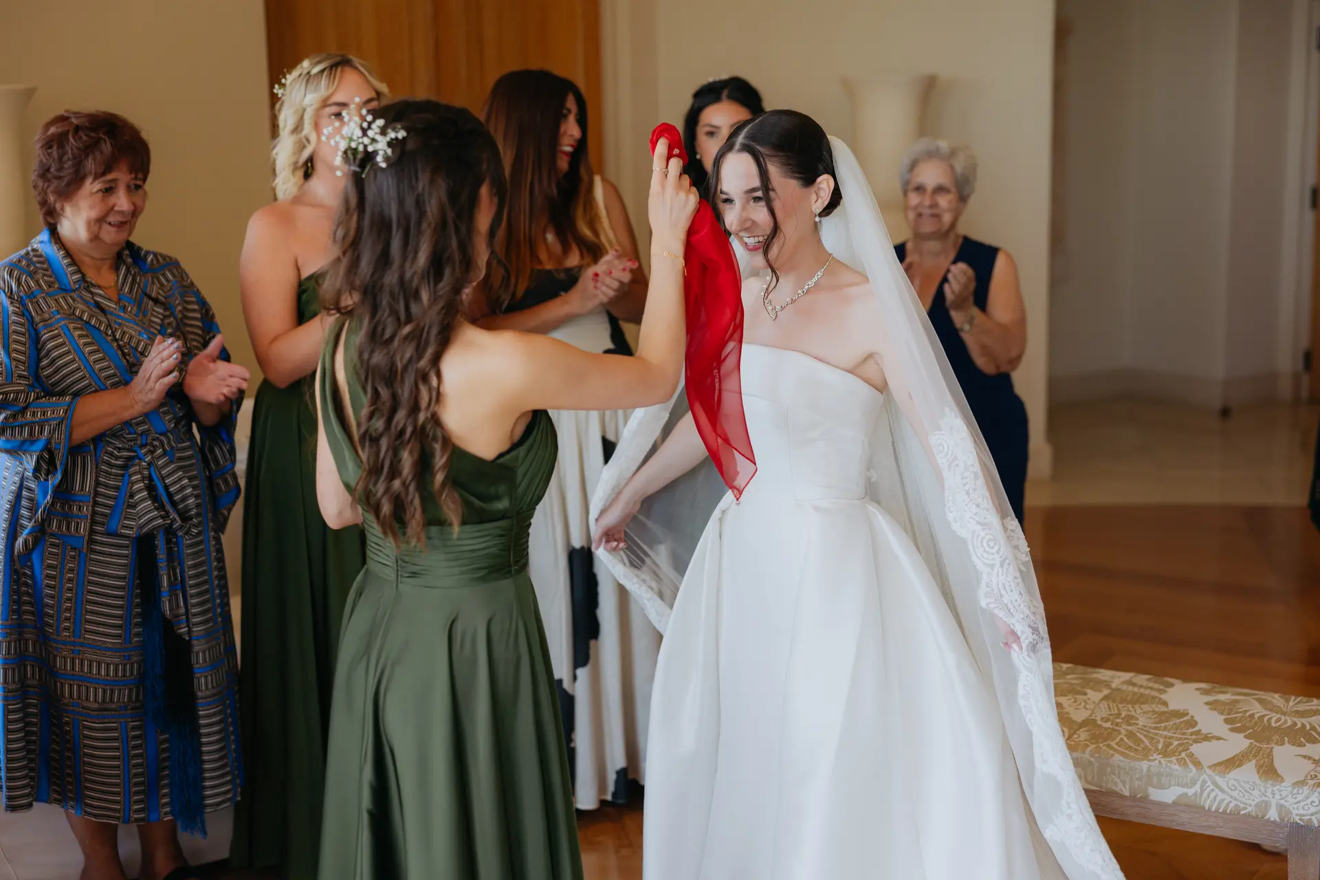 Bride having a red ribbon tied by family during a traditional blessing