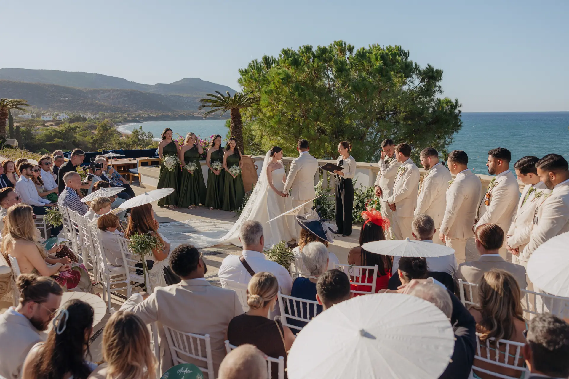 Ceremony terrace at Anassa with guests under white parasols, sea and hills behind