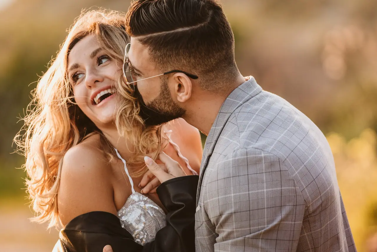 Taha kissing Julia's cheek as she laughs in golden light