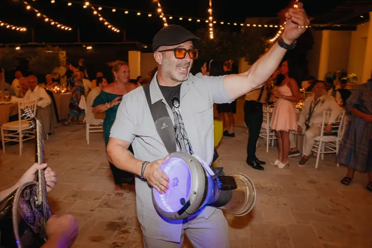 Percussionist dancing between the tables with his drum