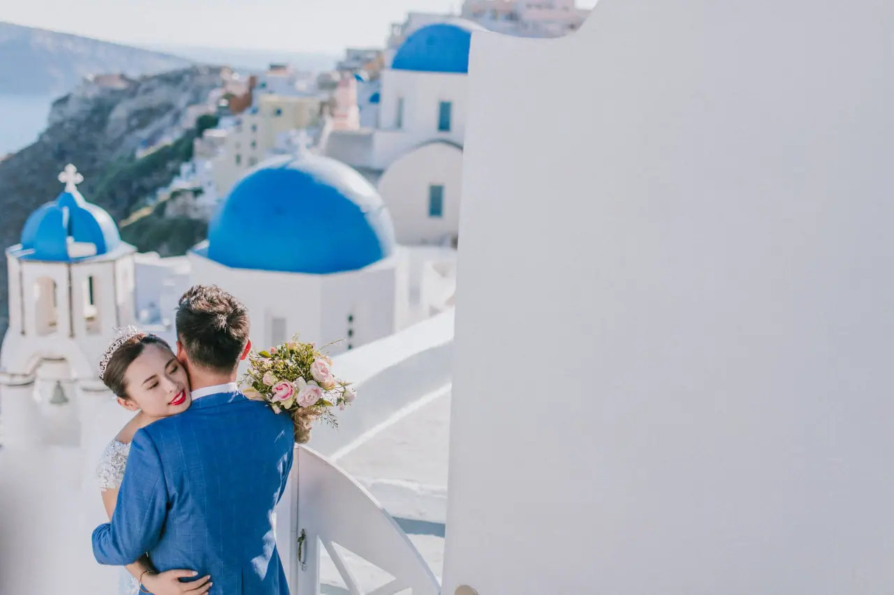 Couple embracing before the blue-domed churches of Santorini, Greece