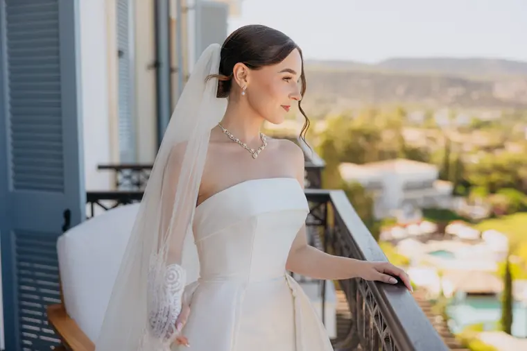 Poppy on the balcony in her gown and veil, gardens and hills beyond