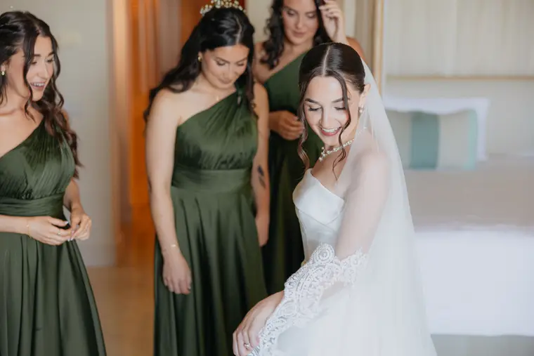 Bridesmaids in green gathered around Poppy as she smiles