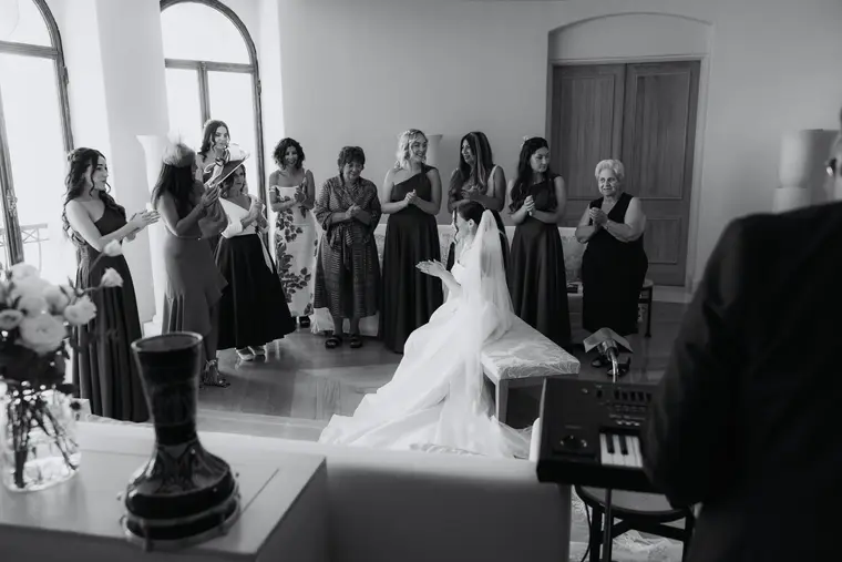 Black-and-white photo of family and bridal party gathered around the seated bride