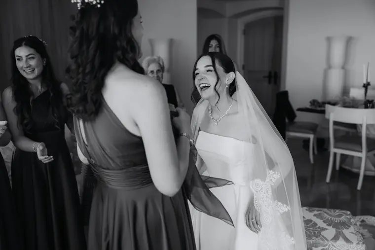 Black-and-white photo of Poppy laughing with bridesmaids during the blessing