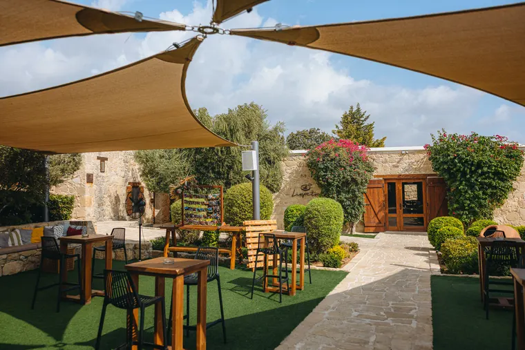 Shaded lounge with shade sails, high tables and stone walls at Liopetro, Kouklia