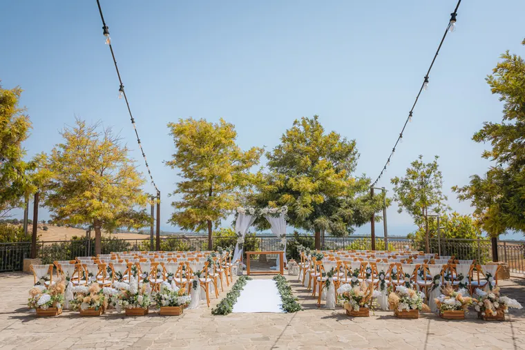 Ceremony aisle lined with flowers and wooden chairs under string lights at Liopetro, Kouklia