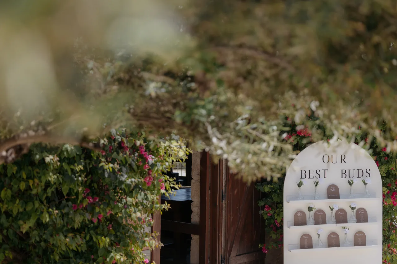 Our Best Buds seating plan sign beside a doorway draped in greenery at Liopetro, Kouklia